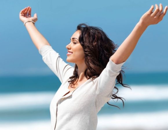 1366882611-happy-woman-arms-outstretched-on-beach